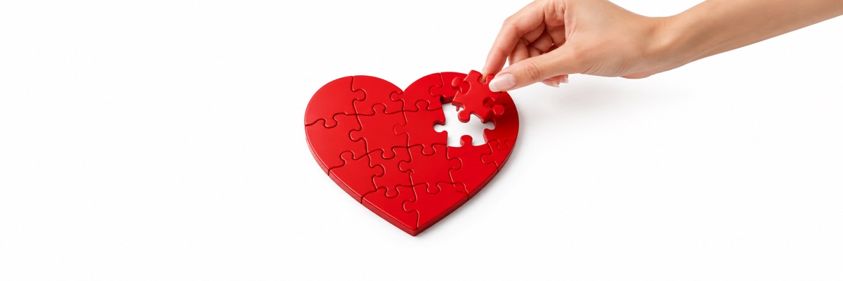 A final puzzle piece being placed into a red heart puzzle on a white background